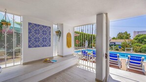 Un balcón amplio con piscina, paredes blancas y un muro de azulejos azules con diseño.