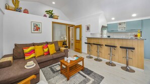 Una sala de estar moderna con sofá, mesa de centro y una zona de cocina con taburetes de bar.
