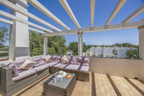 A covered outdoor seating area with wicker furniture and a view of the city. - Villa Flor by Villa Plus (Guia)
