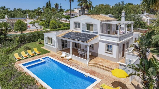 Une maison à deux étages dotée d’une piscine, d’un espace extérieur aménagé et de panneaux solaires.