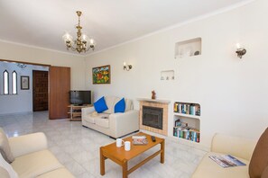 Una sala de estar con chimenea, televisor y estantería.