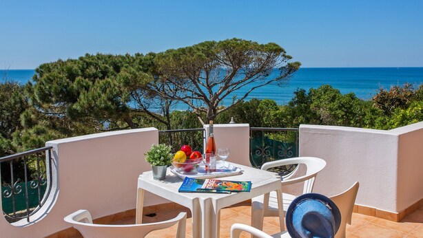 Un balcone con un tavolo apparecchiato per due, vista sulla costa.