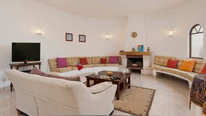 Sala de estar com sofá, mesa de centro, lareira e televisão.