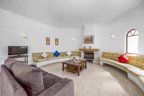 A living room with a television, sofas, a fireplace, and wall-mounted lights.