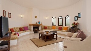 Uma sala de estar com um sofá, uma mesa de centro, uma lareira e uma televisão.