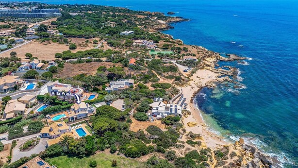 Vista aérea de uma propriedade costeira com vilas, uma praia e uma grande massa de água.
