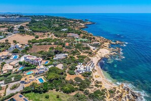 An aerial view of a coastal property with villas, a beach, and a large body of water. - Villa Praia by Villa Plus (Algarve)