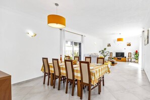 A dining area with a checkered tablecloth, wooden chairs, and a large orange pendant light.