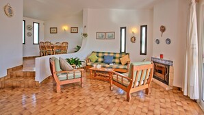 Una sala de estar acogedora con un sofá, sillas, una chimenea y un comedor con mesa y sillas.