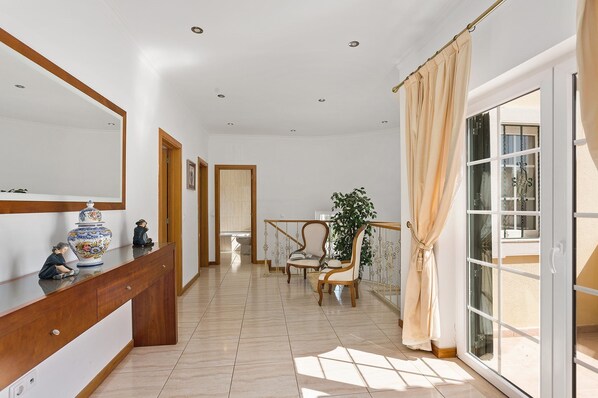 A spacious hallway with a wooden console table, a large mirror, and a potted plant.