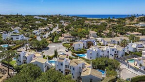 Ein Wohngebiet mit weißen Gebäuden, einem Swimmingpool und Blick auf das Meer.