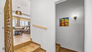 A staircase leading to a living area with a sofa and a painting on the wall. - Villa Sawadi by Villa Plus (Praia do Carvoeiro)