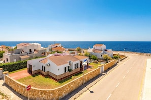 Ein Küstenwohngebiet mit weißen Gebäuden, blauem Himmel und Blick auf das Meer.