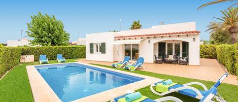 A swimming pool with lounge chairs and a patio area with outdoor furniture.
