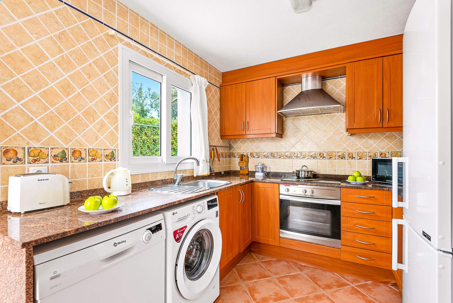 A compact kitchen with a washing machine, a stove, and a microwave.