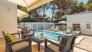 A poolside area with wicker furniture, a pool, and a covered patio. - Villa Casa Feliz by Villa Plus (Son Parc)