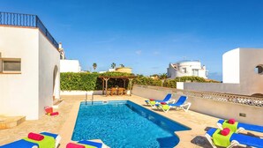A swimming pool with lounge chairs and a pergola.
