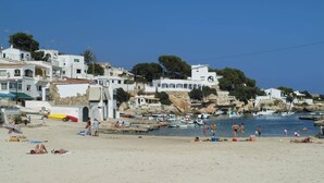 A coastal town with white buildings, a sandy beach, and boats in the water.