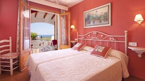 A bedroom with two beds, a balcony with a table and chairs, and a view of the sea. - Villa Corina by Villa Plus (Alayor)