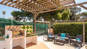 An outdoor patio with a grill, wicker furniture, and a pergola. - Villa Fernando by Villa Plus (S'Algar)