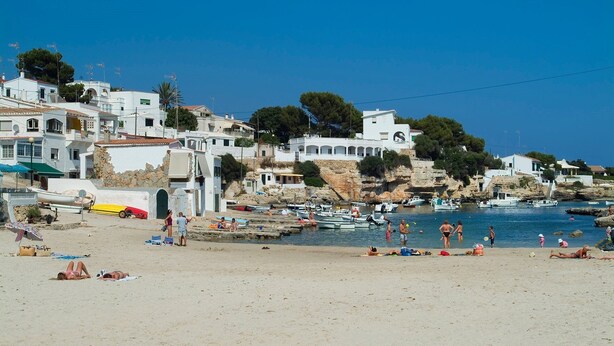 A coastal town with white buildings, a sandy beach, and boats in the water. - Villa Fernando by Villa Plus (S'Algar)