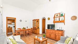 A living room with a sofa, coffee table, TV, and wooden cabinets. - Villa Jessica by Villa Plus (Cap d'Artrutx)