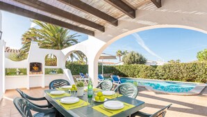 An outdoor dining area with a pool in the background. - Villa Jessica by Villa Plus (Cap d'Artrutx)