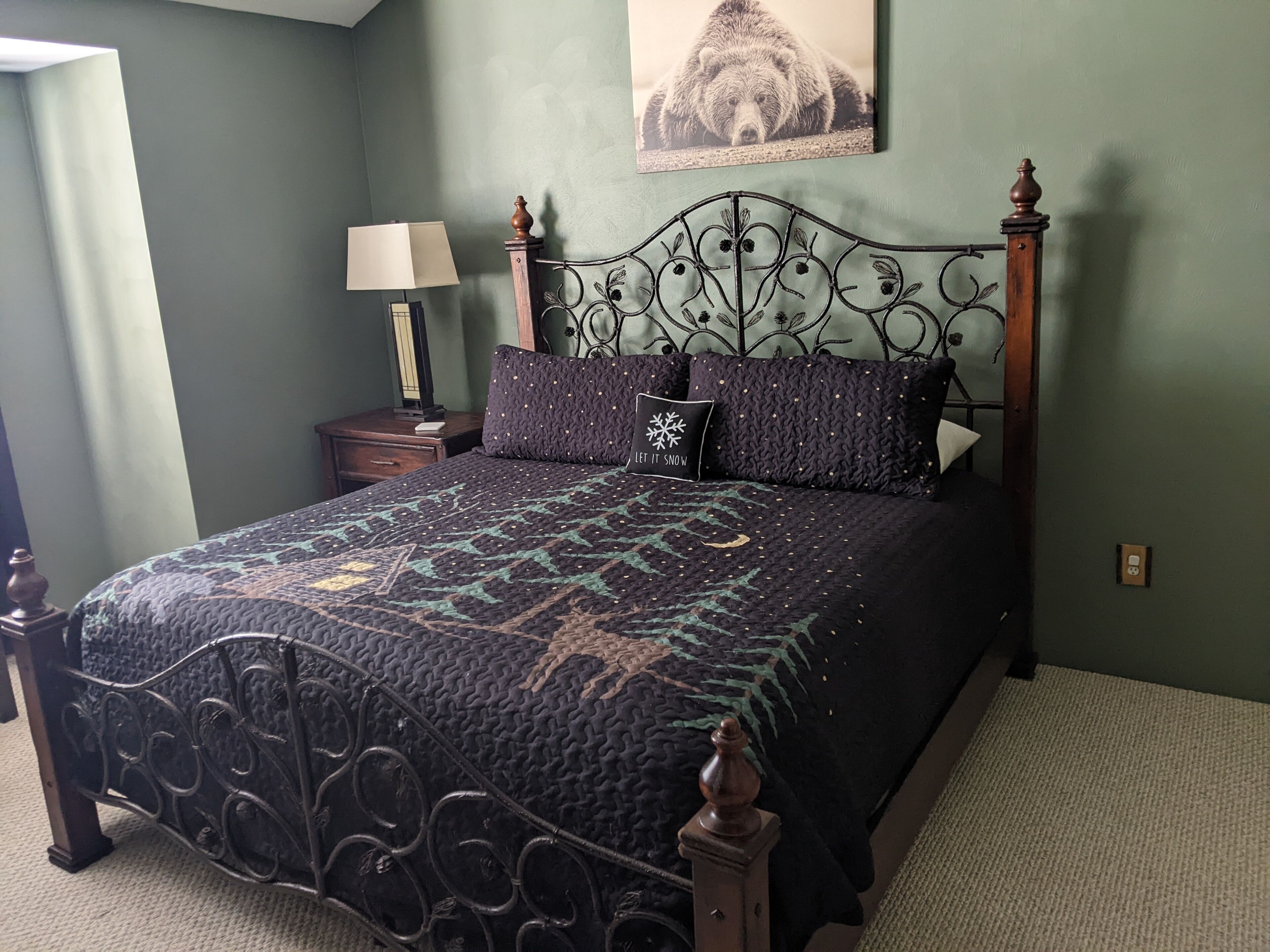 A bedroom with a bed, a nightstand, a lamp, and a wall-mounted picture.