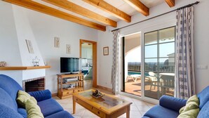 A living room with a fireplace, a television, and a balcony with outdoor furniture. - Villa Laurel by Villa Plus (Alayor)