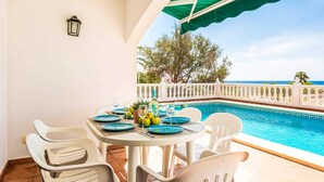 A dining area with a table set for two, overlooking a pool and the sea. - Villa Laurel by Villa Plus (Alayor)