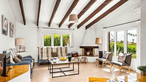 Un salón espacioso con chimenea, ventanas amplias y un techo alto con vigas a la vista.