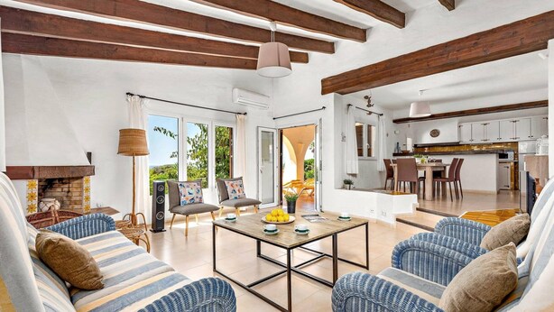 Amplia sala de estar con chimenea, una mesa de comedor y una cocina al fondo.