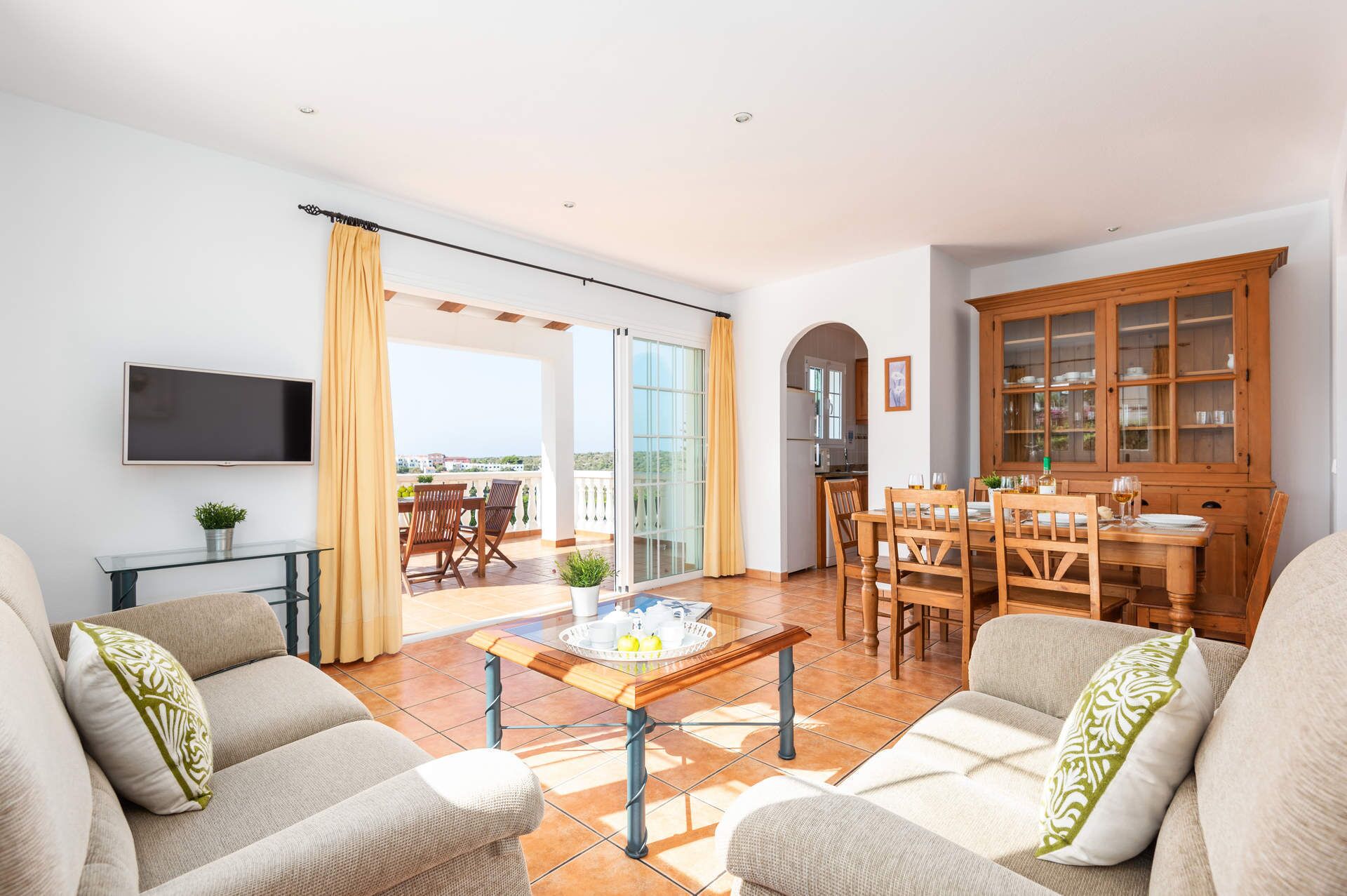 Een woonkamer met een zithoek, een salontafel en een eetgedeelte met stoelen en een tafel.