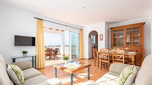 A living room with a sofa set, a coffee table, and a dining area with chairs and a table. - Villa Mirador by Villa Plus (Cala en Porter)