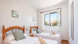 A hotel room with two beds, each with a wooden headboard, white linens, and a view of the outside through a window. - Villa Mirador by Villa Plus (Cala en Porter)