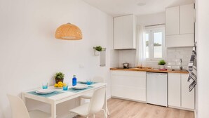 Una cocina moderna con armarios blancos, una encimera de madera y un comedor con mesa y sillas blancas.