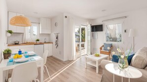 Una cocina moderna con armarios blancos, encimera de madera y una lámpara colgante.
