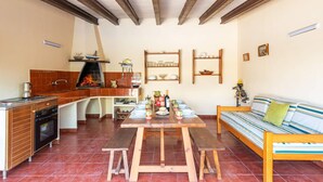 A cozy kitchen with a built-in grill, wooden bench, and a sofa with striped cushions.