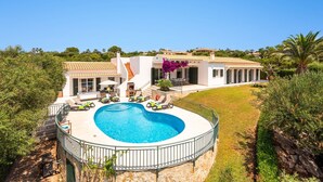Uma villa moderna com piscina circular, área de estar externa e um jardim exuberante.