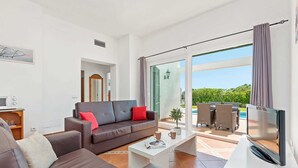 A modern living room with a sofa, coffee table, and a flat-screen TV. - Villa Torrenit by Villa Plus (Alayor)