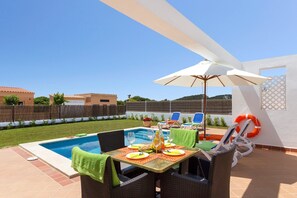 A backyard with a swimming pool, outdoor dining area, and lounge chairs. - Villa Torresoli by Villa Plus (Alayor)