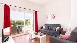 A modern living room with a grey sofa, white coffee table, and red curtains. - Villa Torresoli by Villa Plus (Alayor)