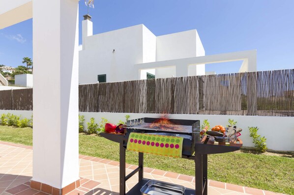 Una parrilla para barbacoa al aire libre con diversos alimentos y un textil decorativo.