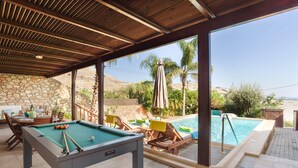Ein Poolbereich mit Billardtisch, Liegestühlen und Blick auf den Pool.