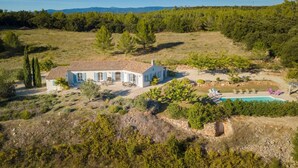 Eine weiße Villa mit einem Ziegeldach, umgeben von einem angelegten Garten und einem Schwimmbecken.