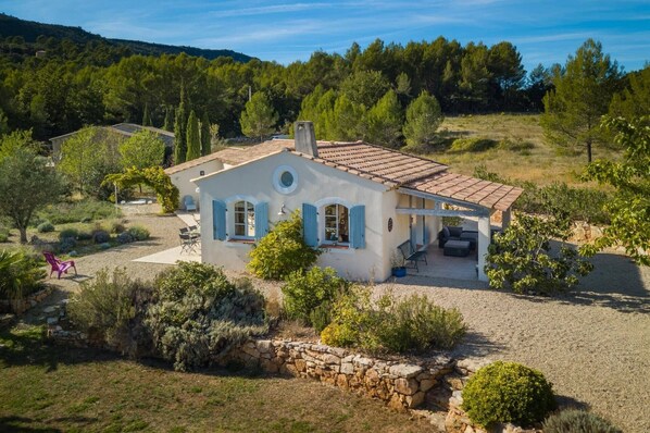 A Mediterranean-style house with a tiled roof, a stone wall, and a gravel driveway.