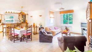 Ein geräumiger Wohnbereich mit Essplatz für vier Personen, einer Couch und einem Couchtisch. Es gibt eine Küchenzeile mit Fenster und Esstisch.