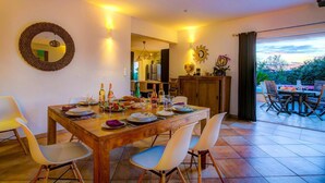 A dining area with a wooden table set for four, a mirror, and a view of the outdoors. - Villa Soleiade by Villa Plus (Saint-Cézaire-sur-Siagne)