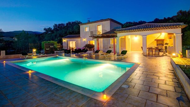 A poolside area with a swimming pool, lounge chairs, and a patio with a table and chairs. - Villa Soleiade by Villa Plus (Saint-Cézaire-sur-Siagne)
