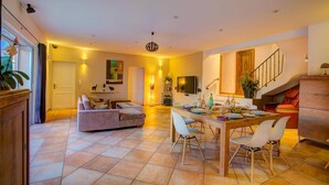 A spacious living area with a dining table, sofas, and a staircase. - Villa Soleiade by Villa Plus (Saint-Cézaire-sur-Siagne)